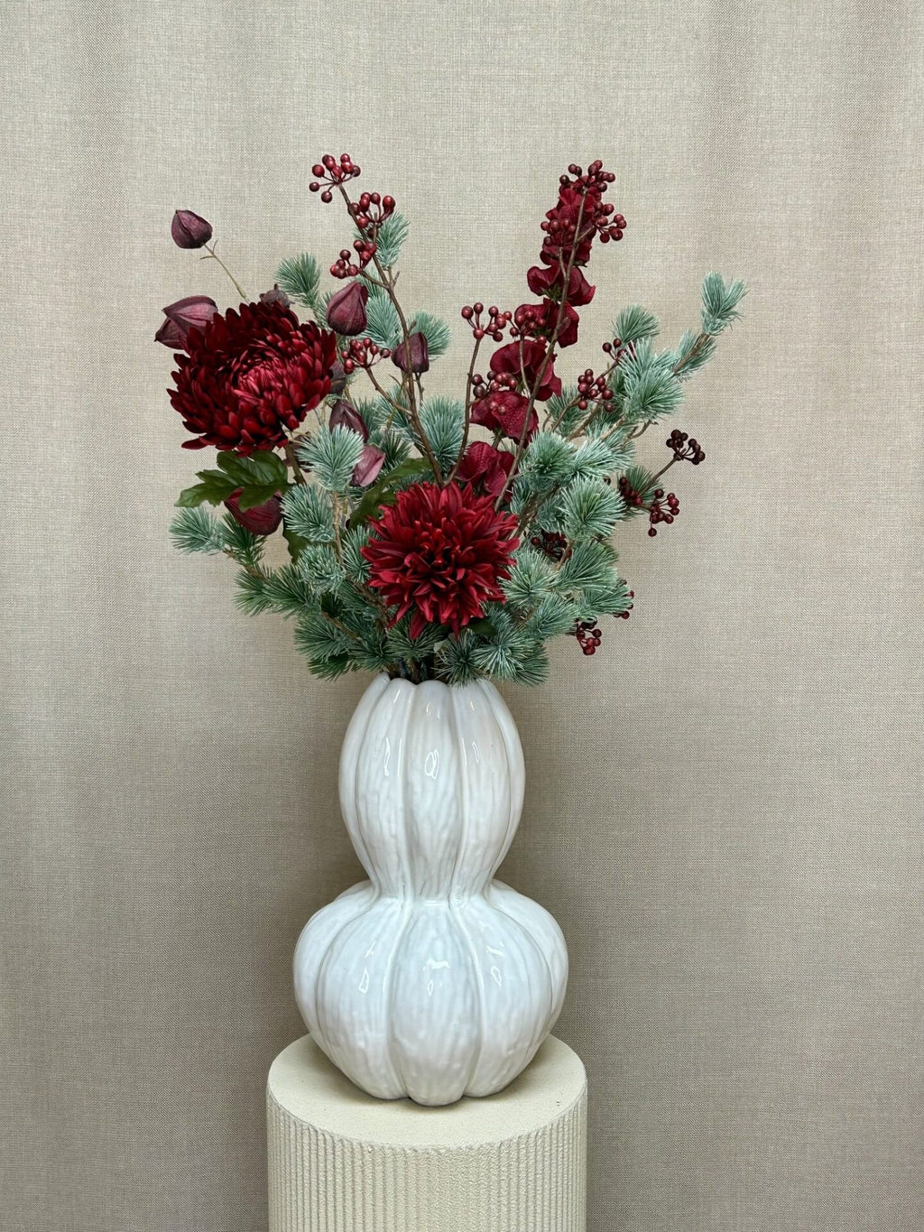 Kunstig bærgren stylet i julebuket med ceder og bordeaux blomster i hvid vase