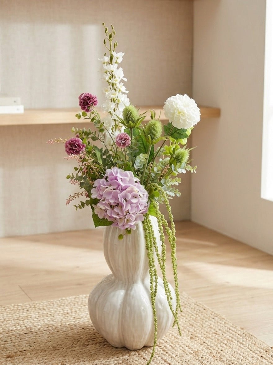 Kunstig eucalyptus gren stylet i vase med blomster