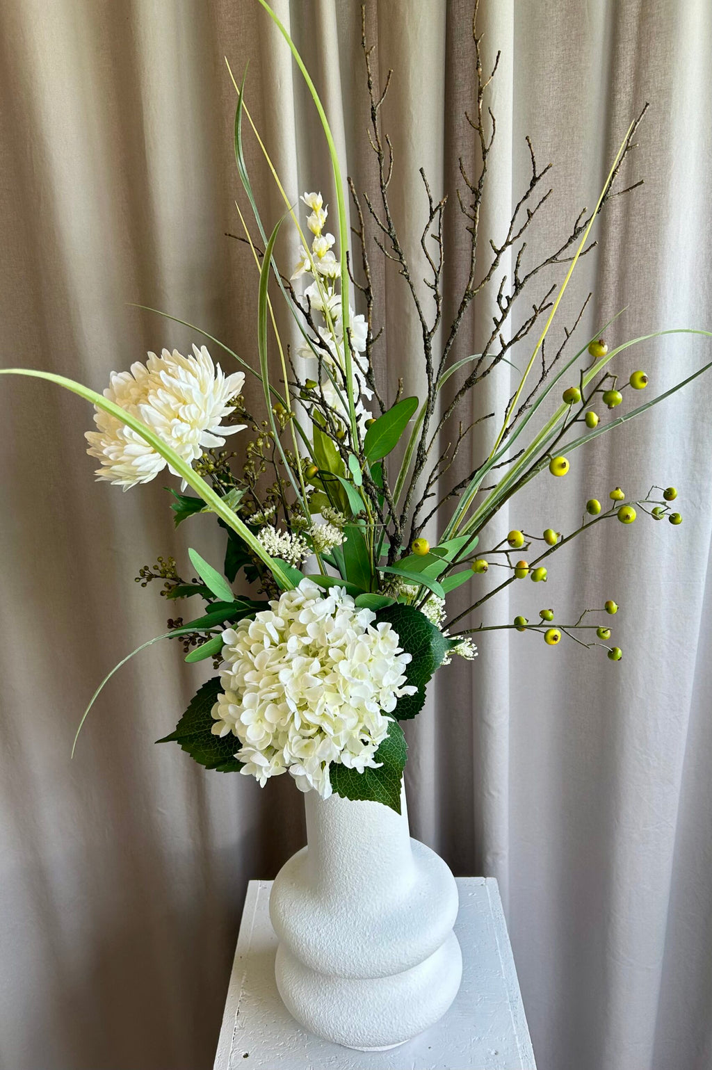 Kunstig hvid hortensia stylet i vase med grønne grene