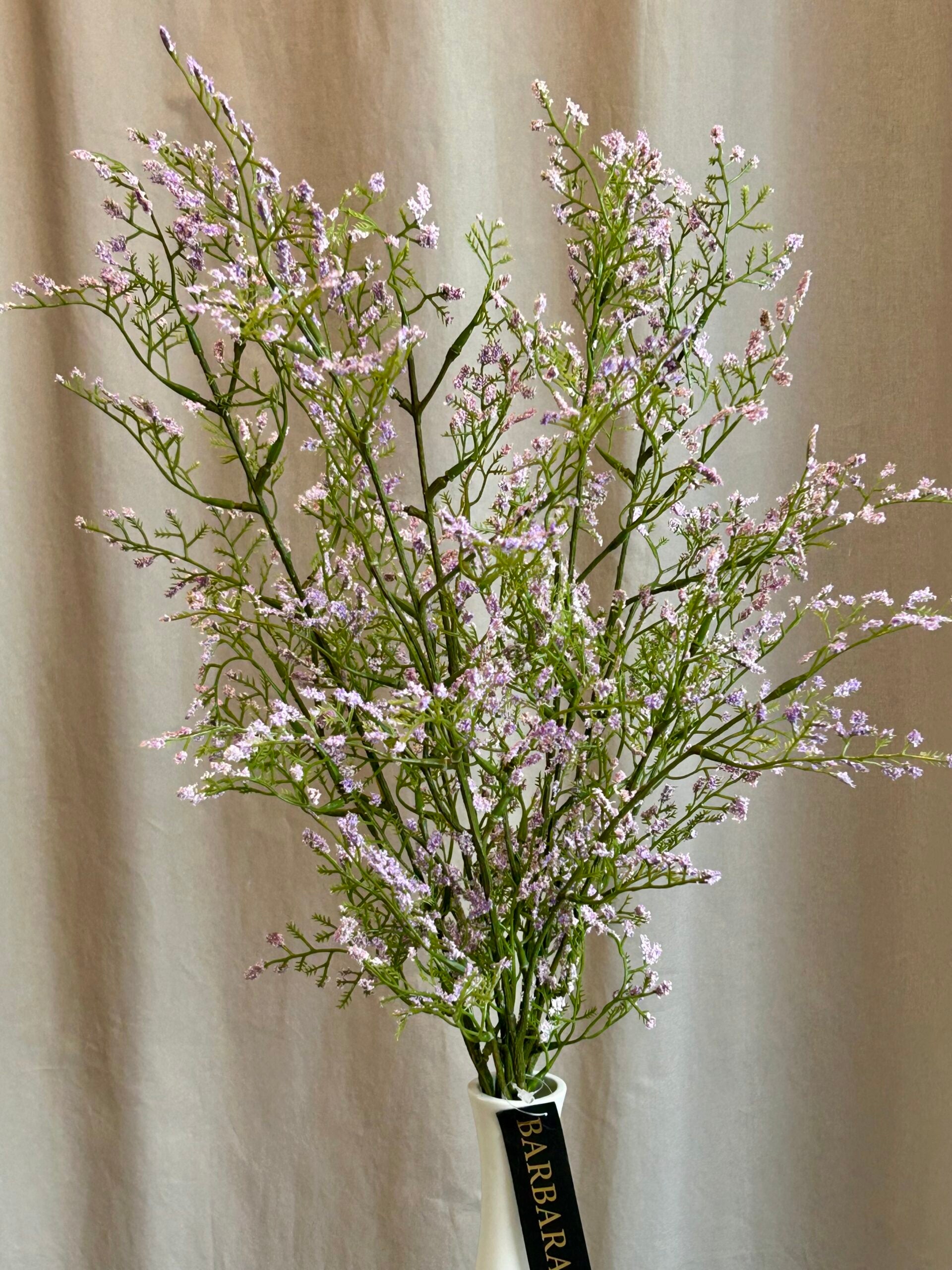 Kunstig limonium gren i lys lilla stylet i vase