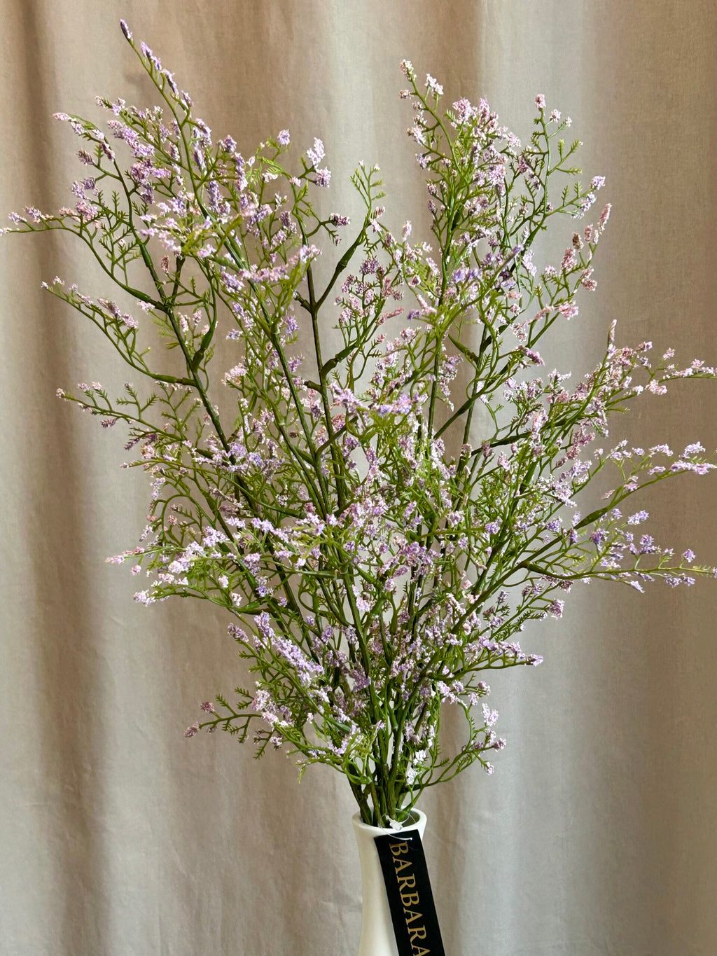 Kunstig limonium gren i lys lilla stylet i vase