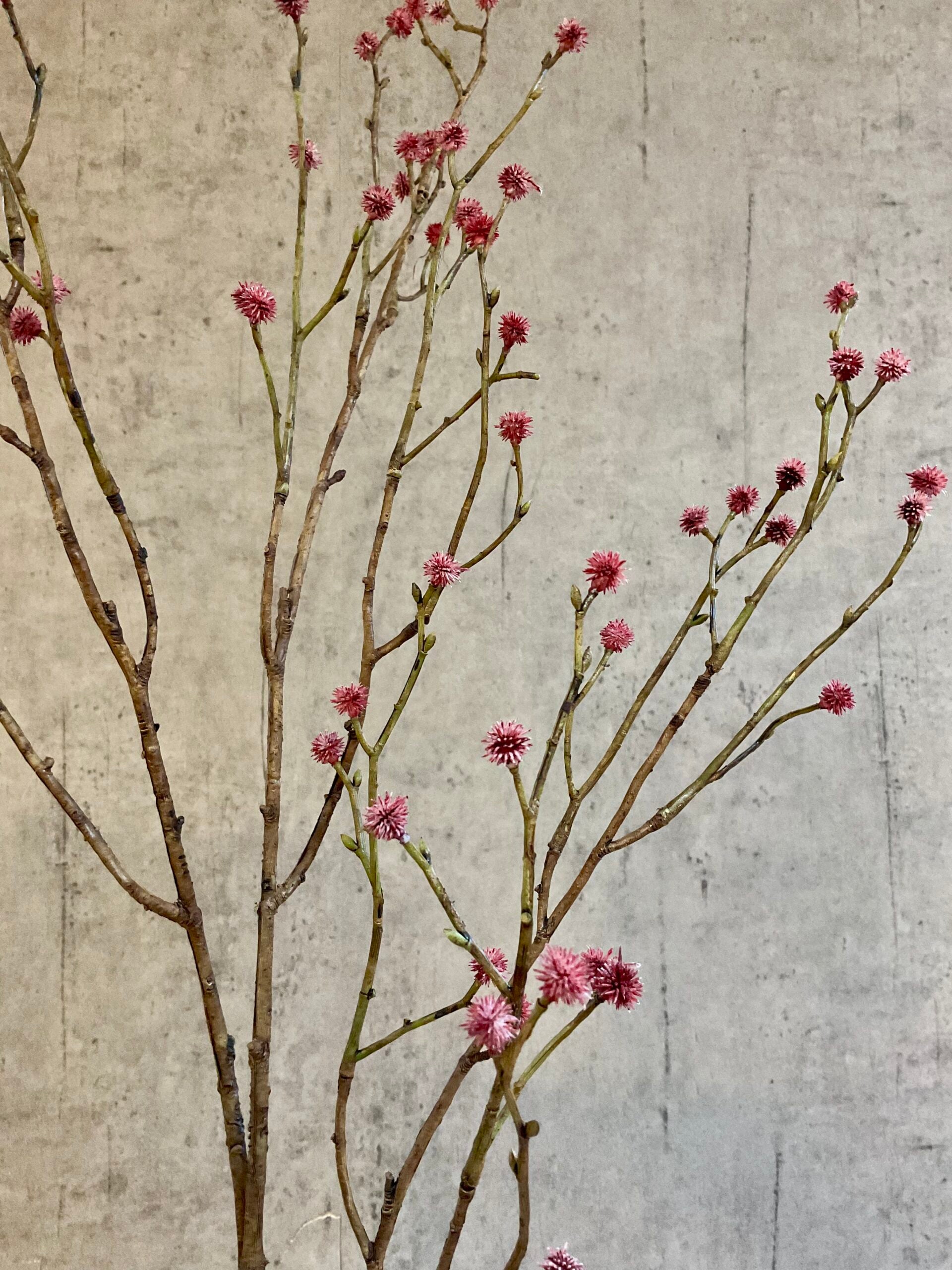 Nærbillede af kunstig mandstro gren med rosa detaljer