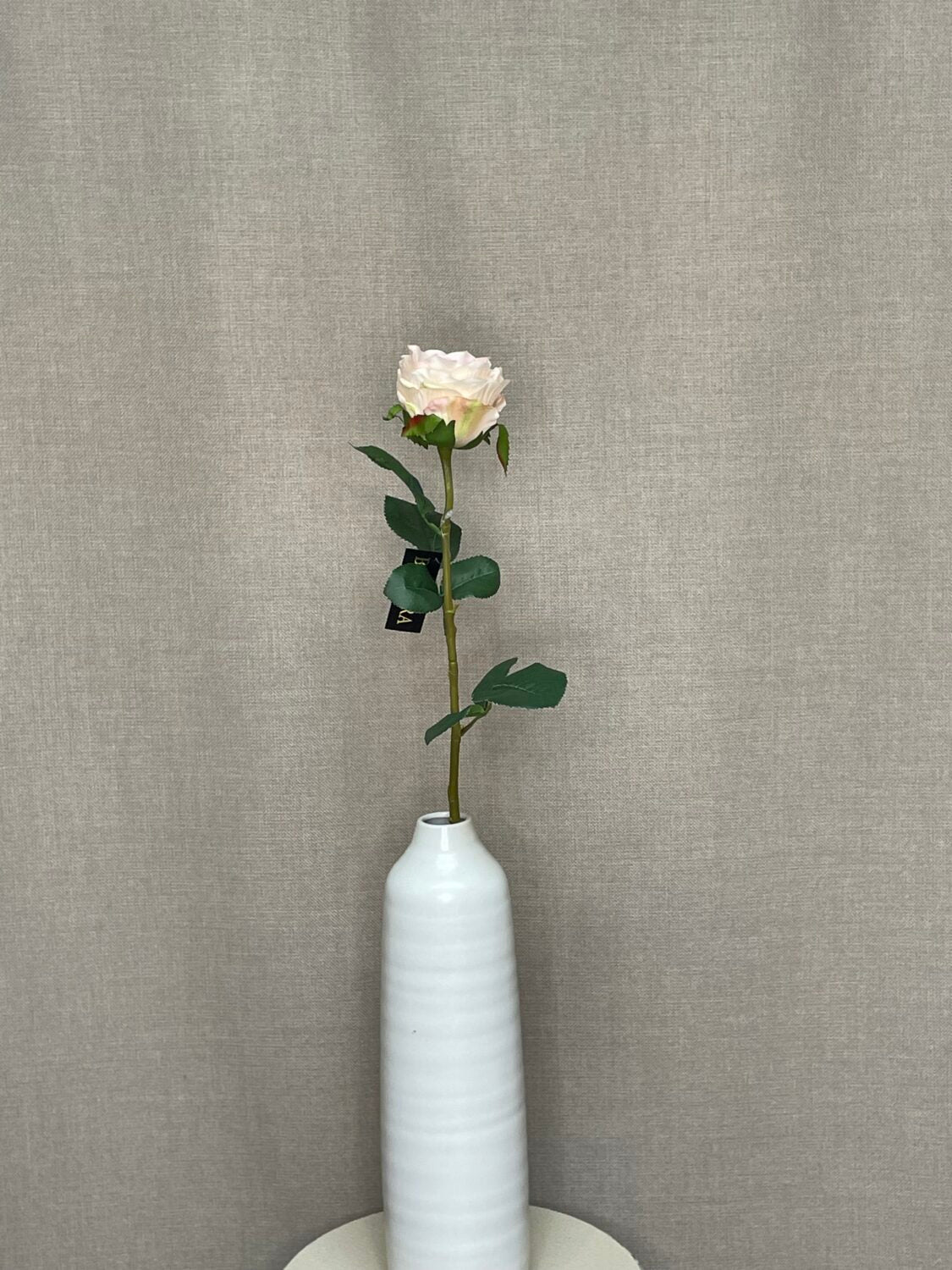 Kunstig cremefarvet rose som enkelt stilk i hvid vase