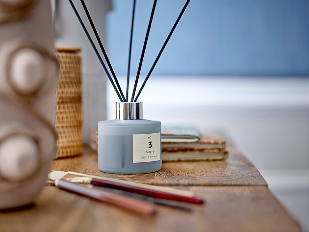 NO. 3 Santal Fig duftpinde i støvet blå glasbeholder på træoverflade – nordisk boligduft fra ILLUME x Bloomingville